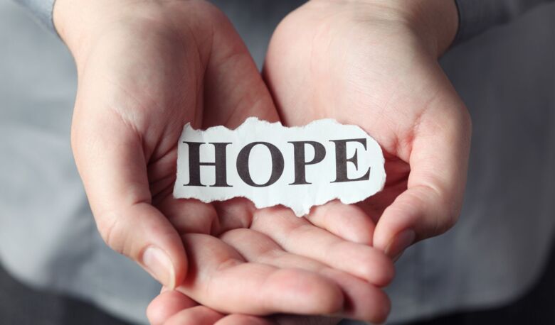 Två händer som håller en papperslapp med texten "hope".