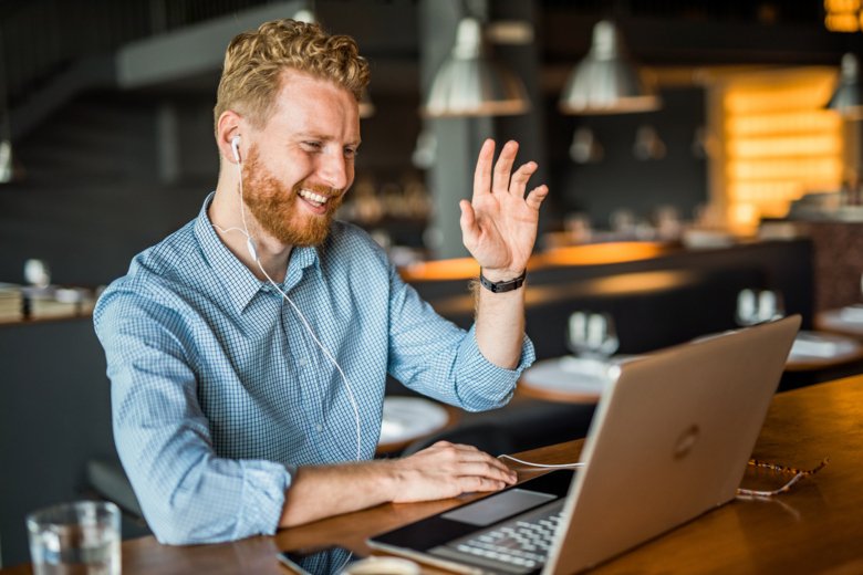 Glad man vinkar till mötesdeltagare via digitalt möte.