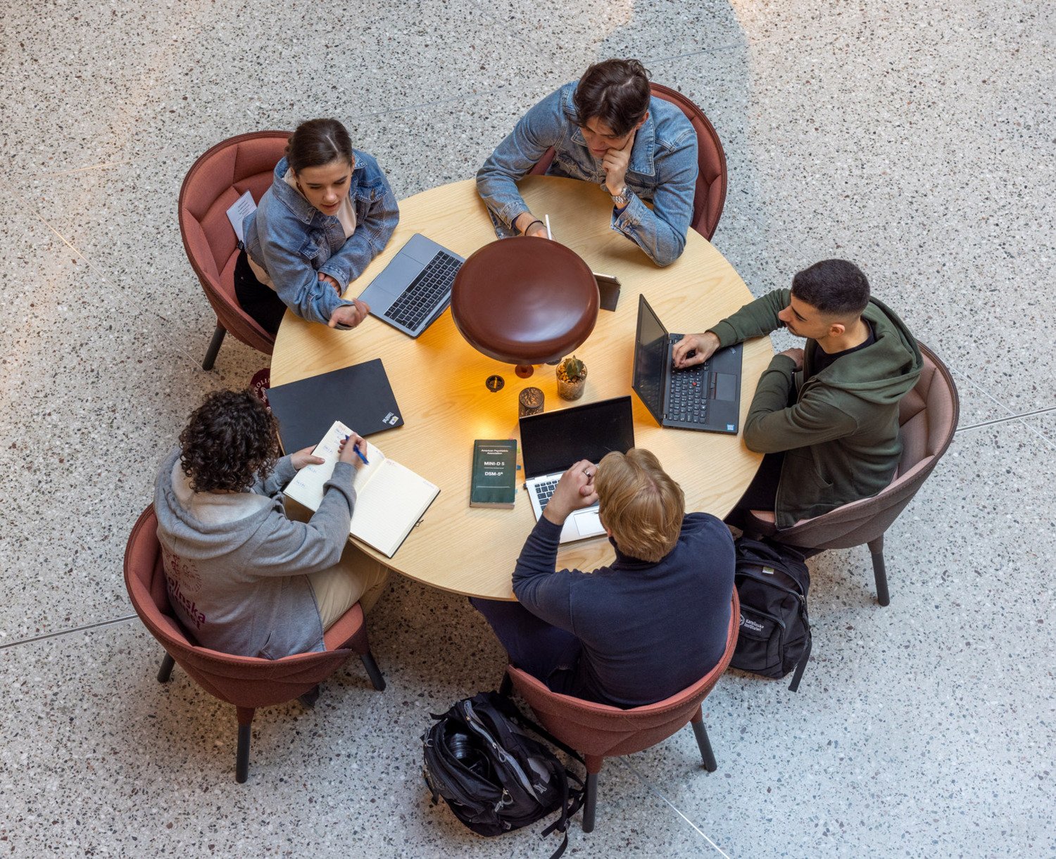 Studenter sitter runt ett bord med sina laptops och pluggar