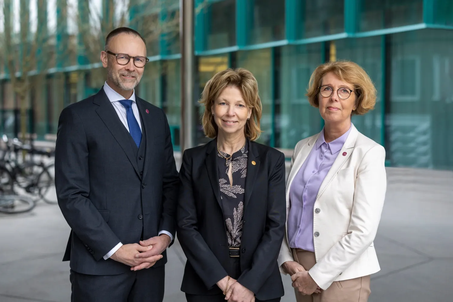 Foto av tre personer framför husfasad.