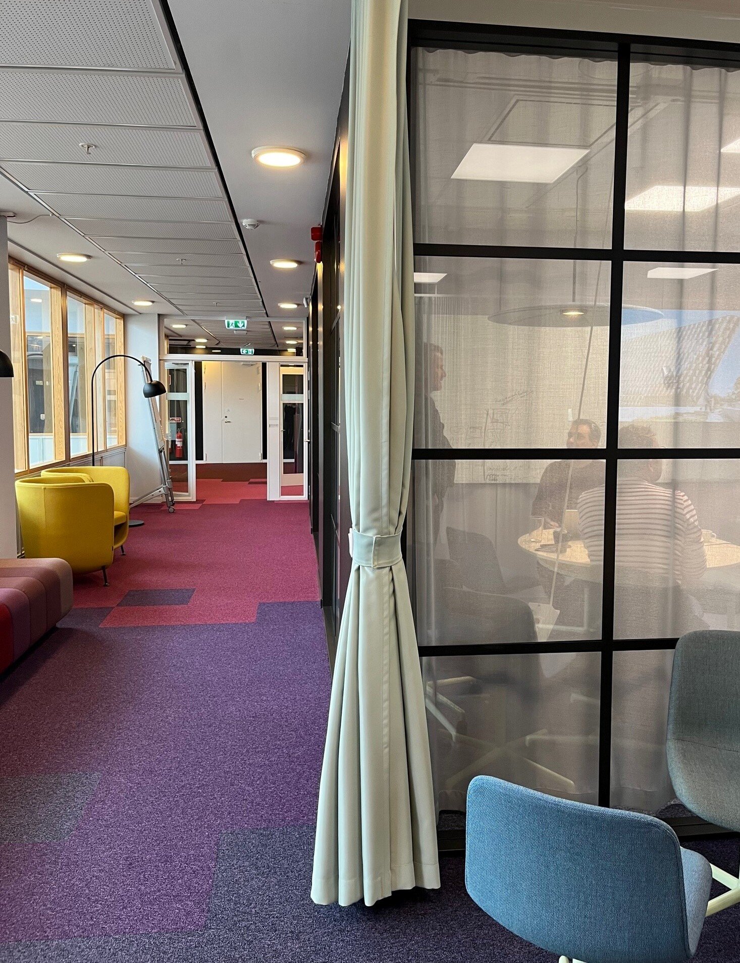 En korridor med fåtöljer och ett mötesrum med glasdörrar hos Enheten för Undervisning och lärande, ANA10.
