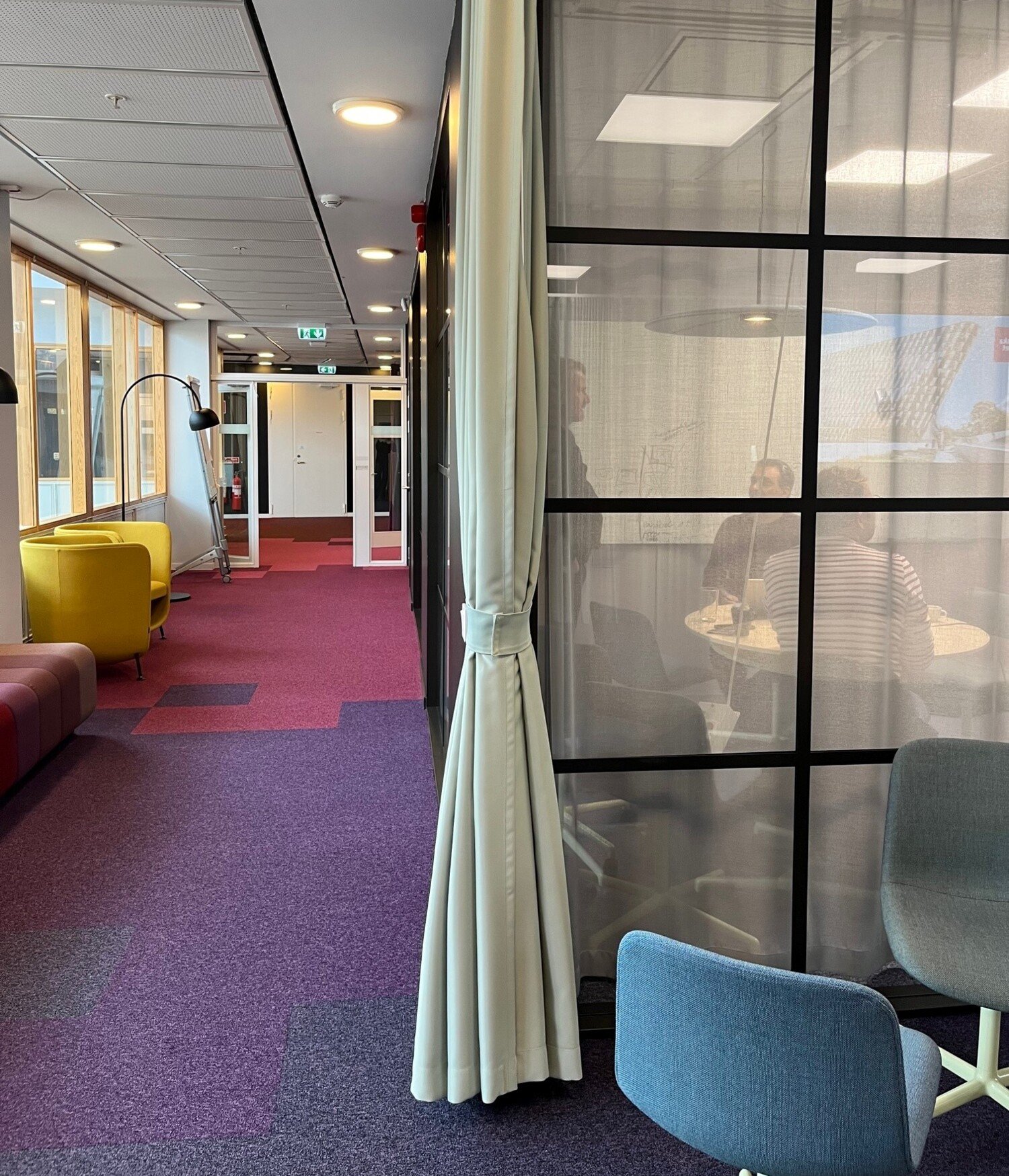 En korridor med fåtöljer och ett mötesrum med glasdörrar hos Enheten för Undervisning och lärande, ANA10.
