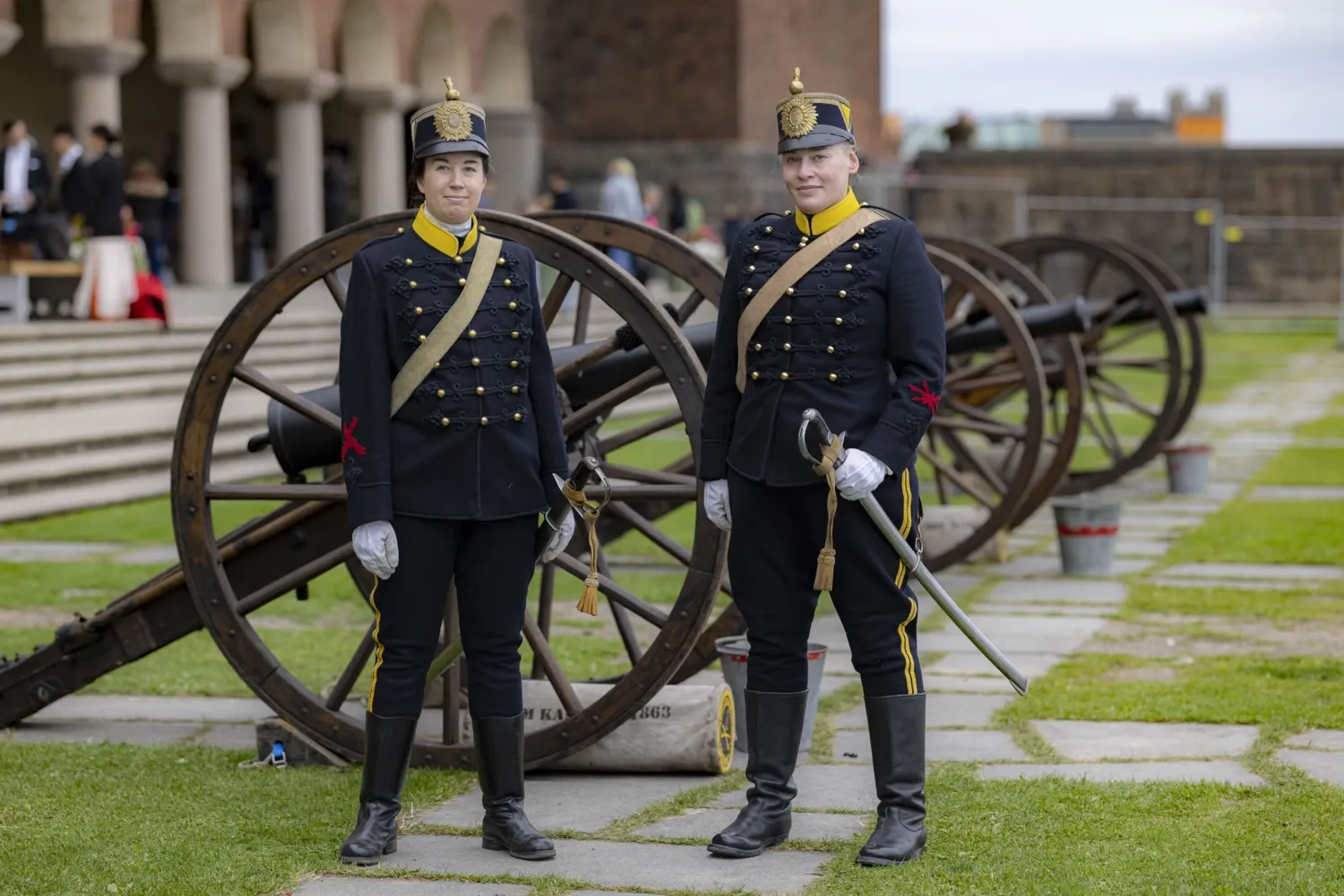 Två personer i högtidsdräkter väntar på att få skjuta salut.