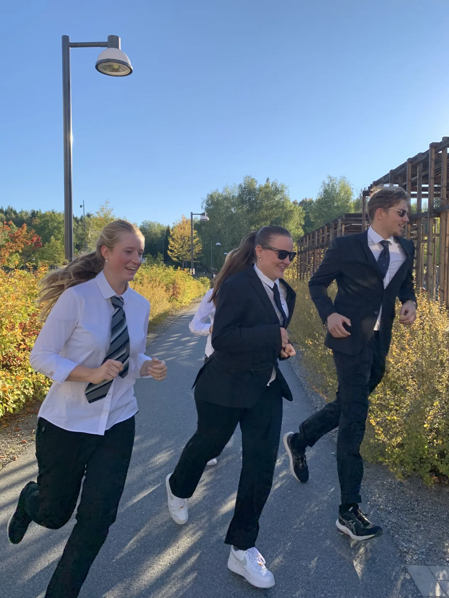 Kvinnliga löpare i skjorta, slips och kavaj tar kurvan med stil