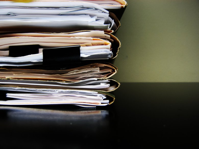 Stack of papers in folders on a table.