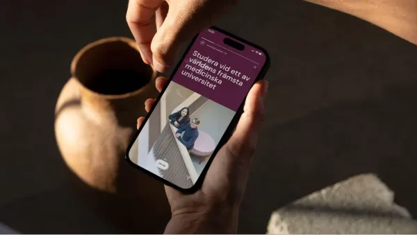 Bilden föreställer en mobiltelefon med två studenter och texten Studera vid världens främsta medicinska universitet