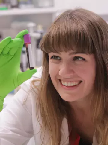 Smiling female scientist examining blood vial
