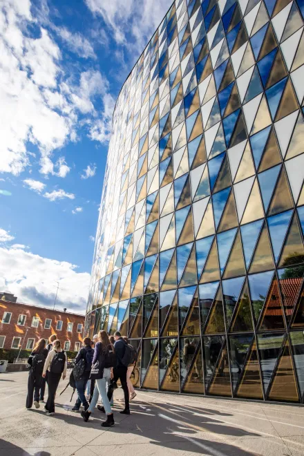 Studenter går framför Aula Medica en solig dag.