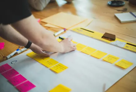 En person skriver på post it-lappar.