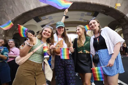 Alina Lapp, Maureen Verdier, Teresa Reindl och Katharina Schormair under paraden på gatan och håller i regnbågsflagor och ler.
